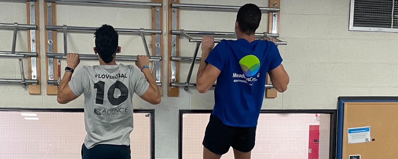 Two students showing off their upper body strength on the pull up bars